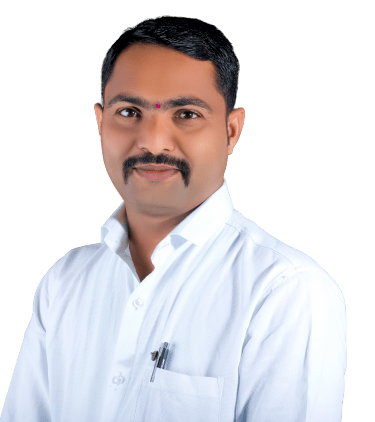 Professional portrait of an Indian man with a mustache wearing a white collared shirt against a black background.