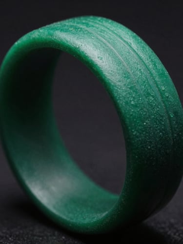 Extreme macro close-up of a green printed resin ring model showing crisp layer lines under dramatic low-key studio lighting with deep shadows
