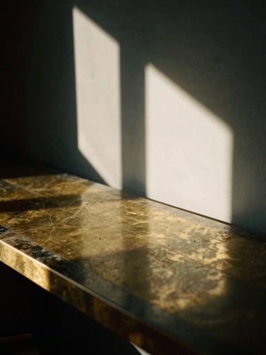Extreme close-up of dramatic window light reflecting off a polished brass and dark marble desk, architectural shadows, moody editorial photography