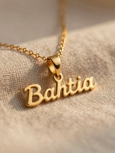 A close-up macro shot of a custom gold nameplate necklace resting on soft natural linen, warm golden-hour sunlight reflecting off the polished metal, shallow depth of field.