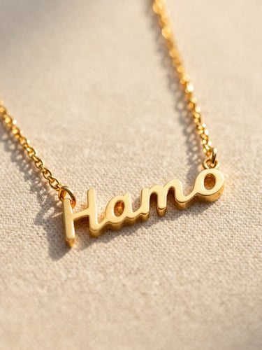 Macro shot of a custom gold nameplate necklace resting on raw linen texture under warm Pacific golden-hour sunlight