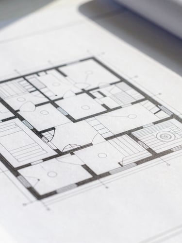 Tight macro detail of a structured architectural blueprint resting on a clean white desk, sharp shadows, bright natural daylight, technical precision.