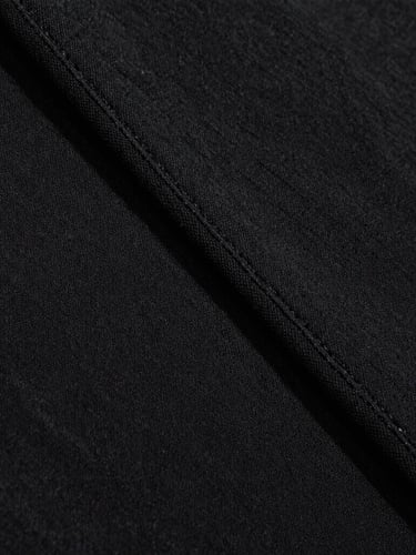 Extreme close-up of heavy black cotton fabric texture, clean double-needle stitching, dramatic side lighting, 35mm film grain
