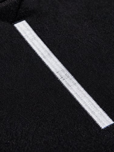 Macro extreme close-up of high-density embroidery on heavy black cotton fabric, sharp studio lighting, dramatic shadows, 35mm film grain