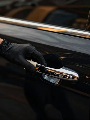 Close-up of a professional detailer's gloved hand polishing the chrome door handle of an immaculate black luxury car, low-key lighting, 35mm