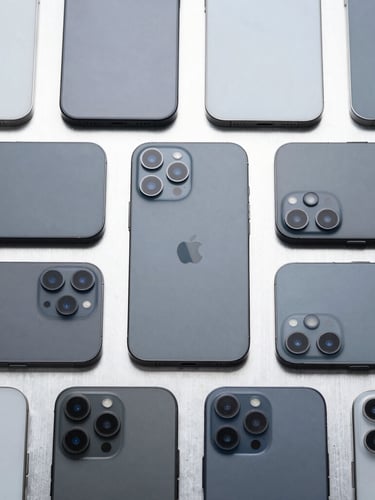 Symmetrical top-down flat lay of multiple slate-colored smartphones aligned on a metallic grid under cool clinical studio lighting.