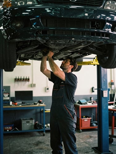 A professional UK mechanic in a dark, high-contrast workshop, working under a car lift with warm overhead lighting, authentic 35mm film style
