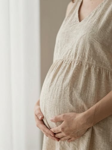 Close-up portrait of a pregnant mother gently holding her belly, soft warm window light, neutral beige linen dress, shallow depth of field, minimalist organic aesthetic