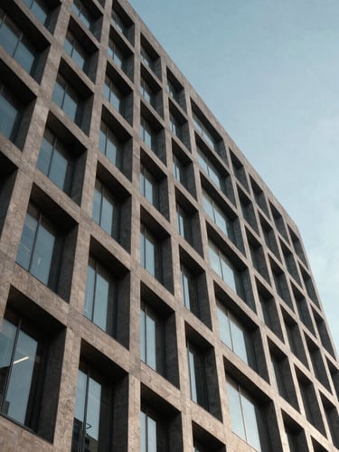 Vista en ángulo contrapicado de la estructura geométrica de un edificio de hormigón y cristal, líneas puras, sombras profundas y luz de día fría.