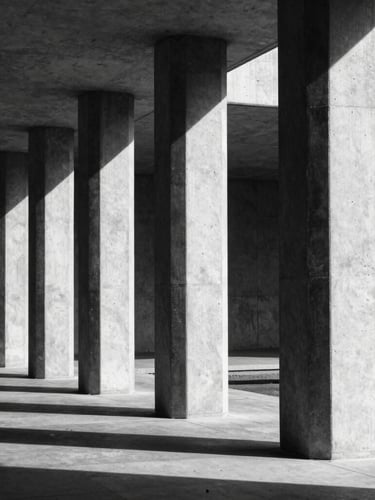 Stark architectural geometry, high-contrast black-and-white concrete pillars casting sharp linear shadows, clinical technical framing.