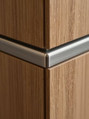 Macro close-up of premium interior material junction — wood veneer panel meeting brushed metal trim, sharp clean edge detail, even north-facing studio light revealing surface grain and texture, no people, architectural photography style
