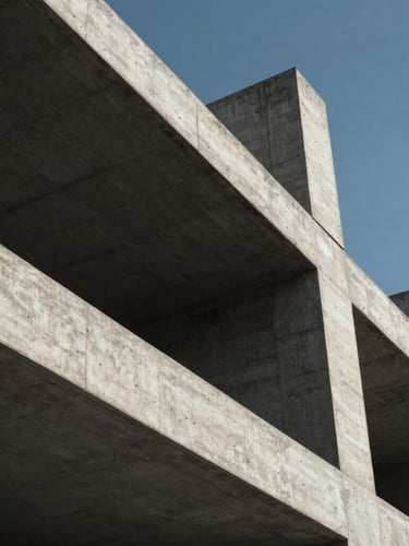 Low-angle architectural photograph of a modern concrete building structure under construction, dramatic shadows, sharp structural lines, natural daylight, high-contrast.