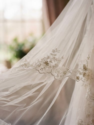 Close-up of a delicate bridal veil, sculpted tulle draped softly, catching diffused window light, shallow depth of field, romantic editorial photography