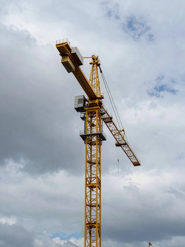 Low-angle shot of a massive yellow tower crane silhouetted against a dramatic overcast Baltic sky in Szczecin port, structural steel details visible, high contrast daylight.