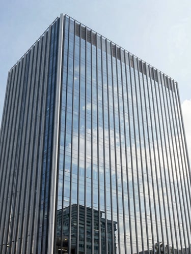 Wide environmental portrait of a modern office glass tower in Davao City, bright daylight, reflections of clouds