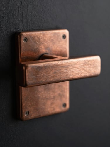 Extreme close-up of a heavy-gauge copper-toned door pull showing metal grain, moody studio lighting, dark background