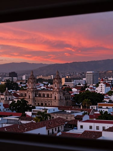 Vista panorámica de Zamora, Michoacán al atardecer, destacando la arquitectura local y un ambiente de crecimiento urbano, con un sutil reflejo de luz roja.