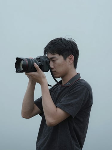 A quiet environmental portrait of a photographer holding a camera, soft cool overcast daylight, minimalist studio setting, desaturated grays and blues