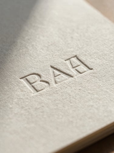 Extreme close-up of embossed stationery on textured linen paper, soft diffused natural daylight, delicate shadows.