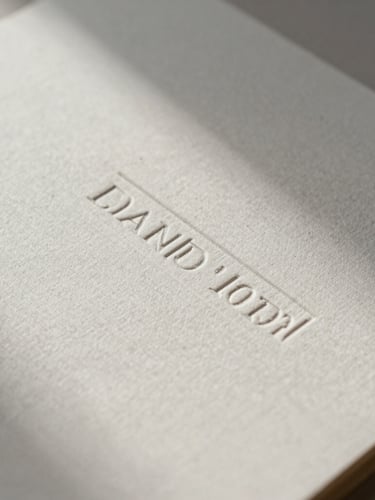 Macro detail of high-end embossed stationery on textured linen paper, soft diffused daylight casting gentle shadows, elegant minimalist composition