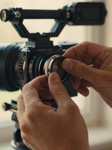 Intimate close-up of hands adjusting a manual focus ring on a high-end cinema camera, warm golden-hour side lighting, shallow depth of field, tactile textures of metal and dust particles.