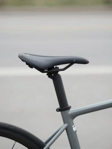 Eye-level medium shot of a modern commuter bicycle detail showing a sleek RealSeat saddle, soft natural overcast daylight, desaturated slate tones, 50mm