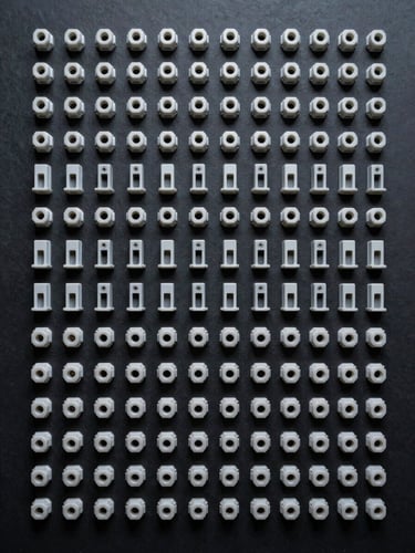 Flat-lay overhead studio shot, organized rows of identical small industrial plastic brackets and connector parts on a dark matte surface, consistent studio strobe lighting highlighting surface uniformity and precision tolerances, cool tones, no hands