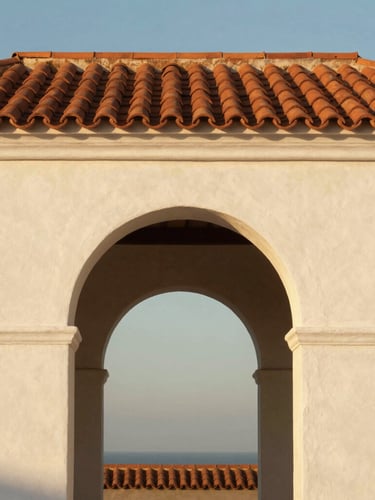 Straight-on architectural crop of a classic white stucco archway framing a terracotta tiled roof, warm late-afternoon golden hour coastal light, high-contrast shadows.