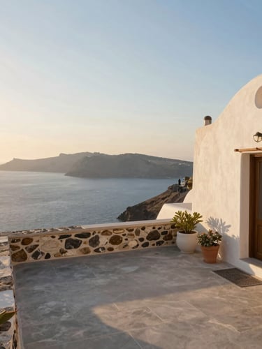 Wide environmental shot of a peaceful Aegean stone villa terrace overlooking the blue sea at golden hour, warm sunlight, soft shadows, inviting atmosphere
