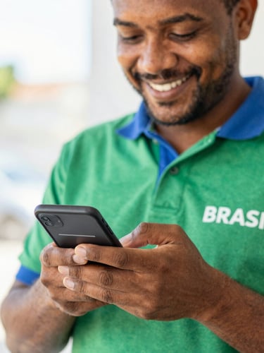 Close-up of a Brazilian worker smiling warmly while looking at a clean banking app interface on their smartphone, bright natural daylight, soft green and blue tones, 35mm lens
