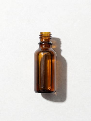 Overhead laboratory-style flat lay of a single amber glass bottle on a clean white stone surface, bright high-key studio light, sharp defined shadows, crisp details, 50mm lens