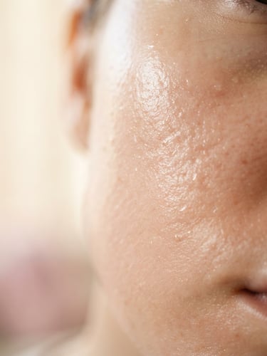 Macro close-up of dewy, hydrated skin showing fine natural texture, soft morning side-light, warm alabaster background, 85mm