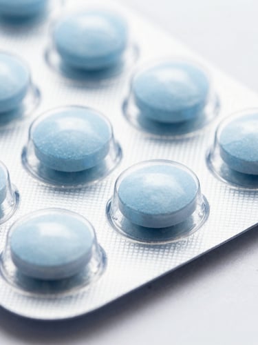 Macro close-up of dry oral solid tablets in clean white blister packs, bright clinical high-key studio light, clinical blue and white tones, sharp detail
