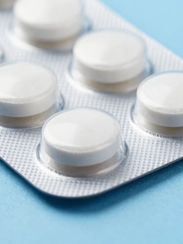 Macro close-up of clean white oral tablets in a blister pack on a sterile blue background, clinical lighting, sharp focus
