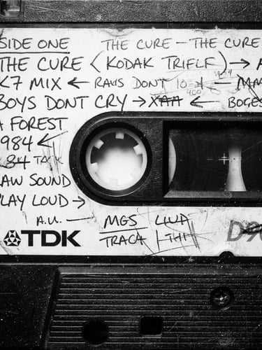 Extreme close-up of a vintage cassette tape shell with hand-written label, harsh direct flash, high contrast monochrome, raw analog grain, 35mm film photography