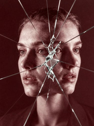Experimental cinema poster — double exposure of a face merging with fractured glass geometry, side-lit, monochrome with deep crimson tint, film grain