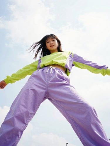 Dynamic low-angle wide-angle 35mm shot of a Gen Z girl in a high-energy pose, wearing electric lavender and digital lime streetwear, bright daylight with high contrast, candid disposable-camera energy.