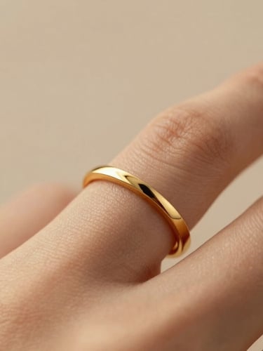 Macro shot of a delicate gold ring on a woman's finger, soft golden-hour side lighting, warm champagne tones, shallow depth of field