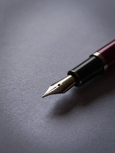 Macro close-up of high-quality textured cotton paper with a classic fountain pen resting on it, soft dramatic side lighting, deep wine and charcoal tones.