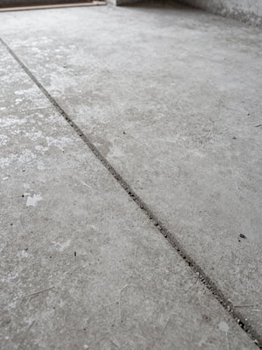 Close-up tight framing of a freshly cleaned concrete floor surface after construction, overcast daylight from left, visible grout lines and no dust, high contrast documentary style