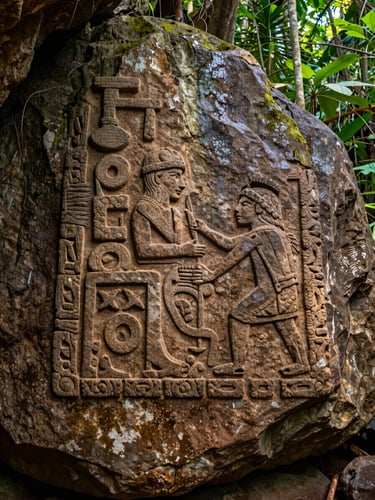 Primer plano de petroglifos taínos tallados en la roca caliza de una cueva protegida, iluminados por un haz de luz natural filtrada, tonos terrosos y textura de piedra húmeda.