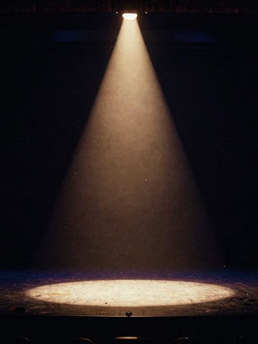 Cinematic wide shot of a classic theatre stage under a single warm tungsten spotlight, dust motes dancing in the beam, deep midnight navy shadows, 35mm film texture.