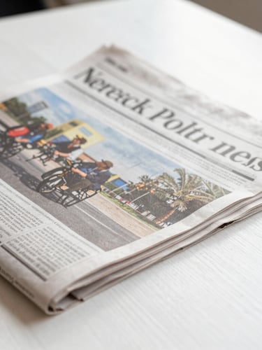 A close-up of a printed newspaper layout resting on a clean white wooden table, sharp editorial photojournalism, bright natural daylight