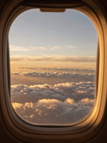 Atmospheric view of a flight deck window looking out to a vast golden-hour horizon over soft layered clouds, cinematic fine-art photography