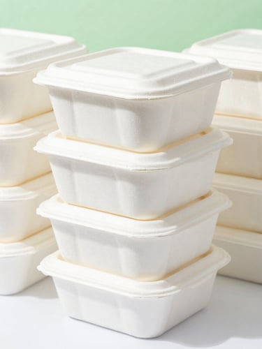 Close-up of neatly stacked biodegradable food containers in bright, natural daylight, crisp white background with subtle green accents