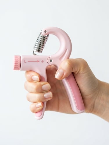 A close-up of a hand holding a stylish pastel-colored grip trainer on a clean white background, soft natural morning light, bright high-key product photography, 50mm lens