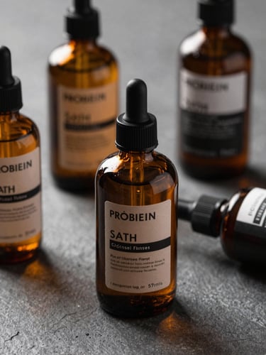 Close-up of premium male grooming products, amber glass bottles on a dark stone surface, soft natural side lighting, textured shadows