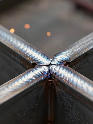 Extreme close-up of a flawless, continuous weld bead joining two thick structural steel channel beams, sparks in background.
