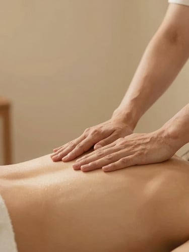 Therapist's hands in precise professional motion applying targeted pressure on a client's back, warm minimalist treatment room, soft indirect glow