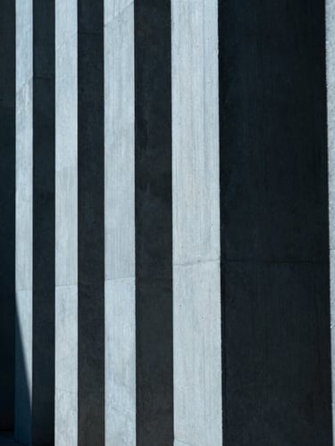 Tight abstract crop of clean concrete architectural columns, sharp geometric shadows, cool blue tone, 35mm lens.